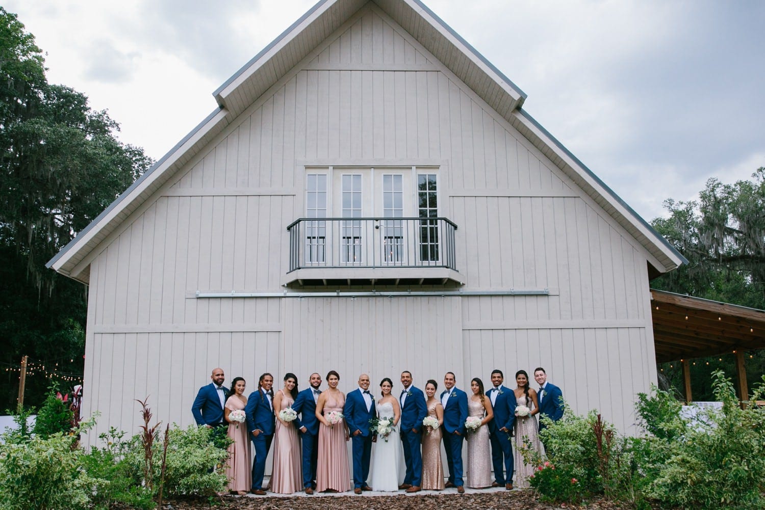 Stunning bridal party wearing blush gowns and royal blue suits at October Oaks Farm. The perfect style for a country chic wedding.