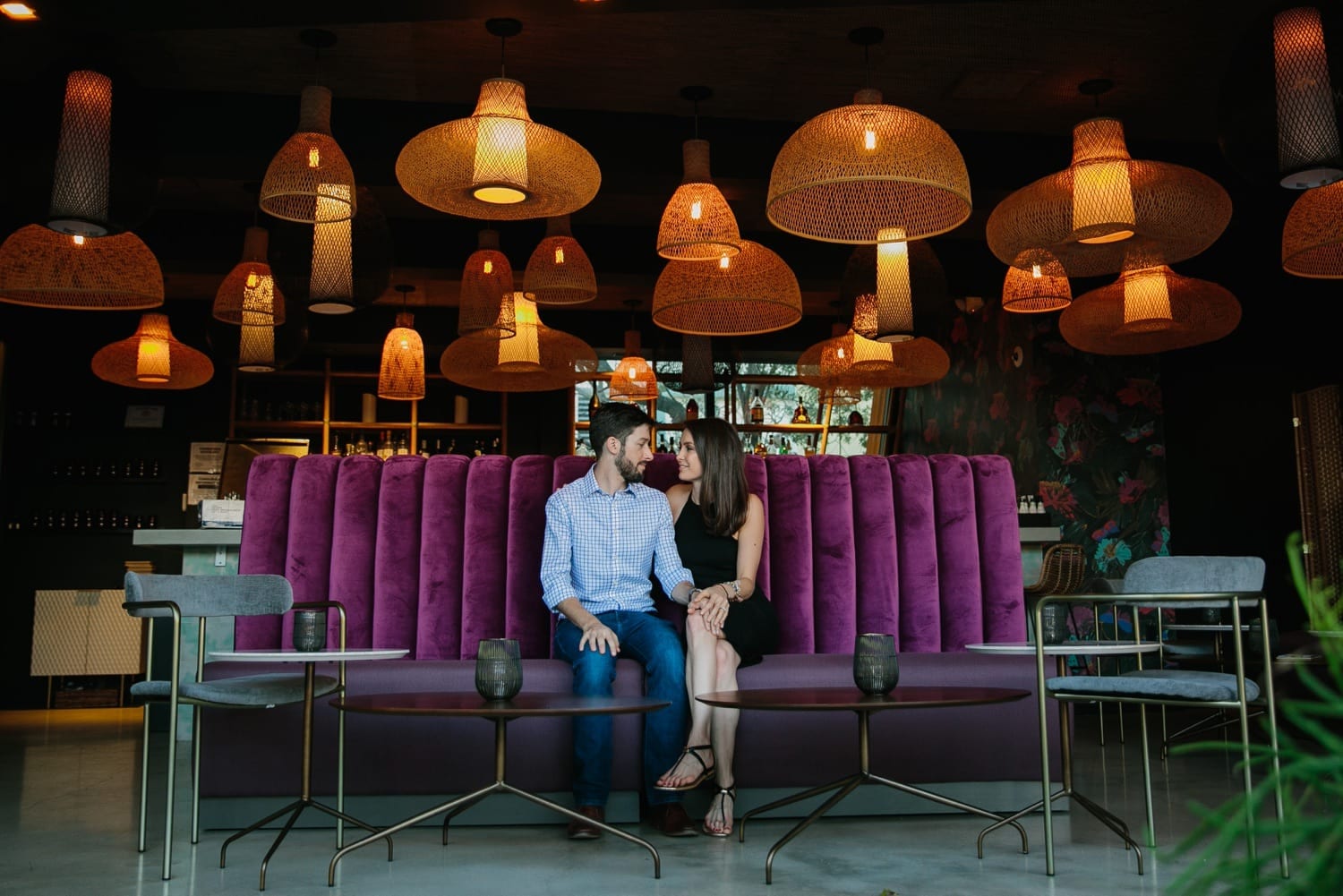 couple sitting on a cool purple couch for their engagement session in Miami
