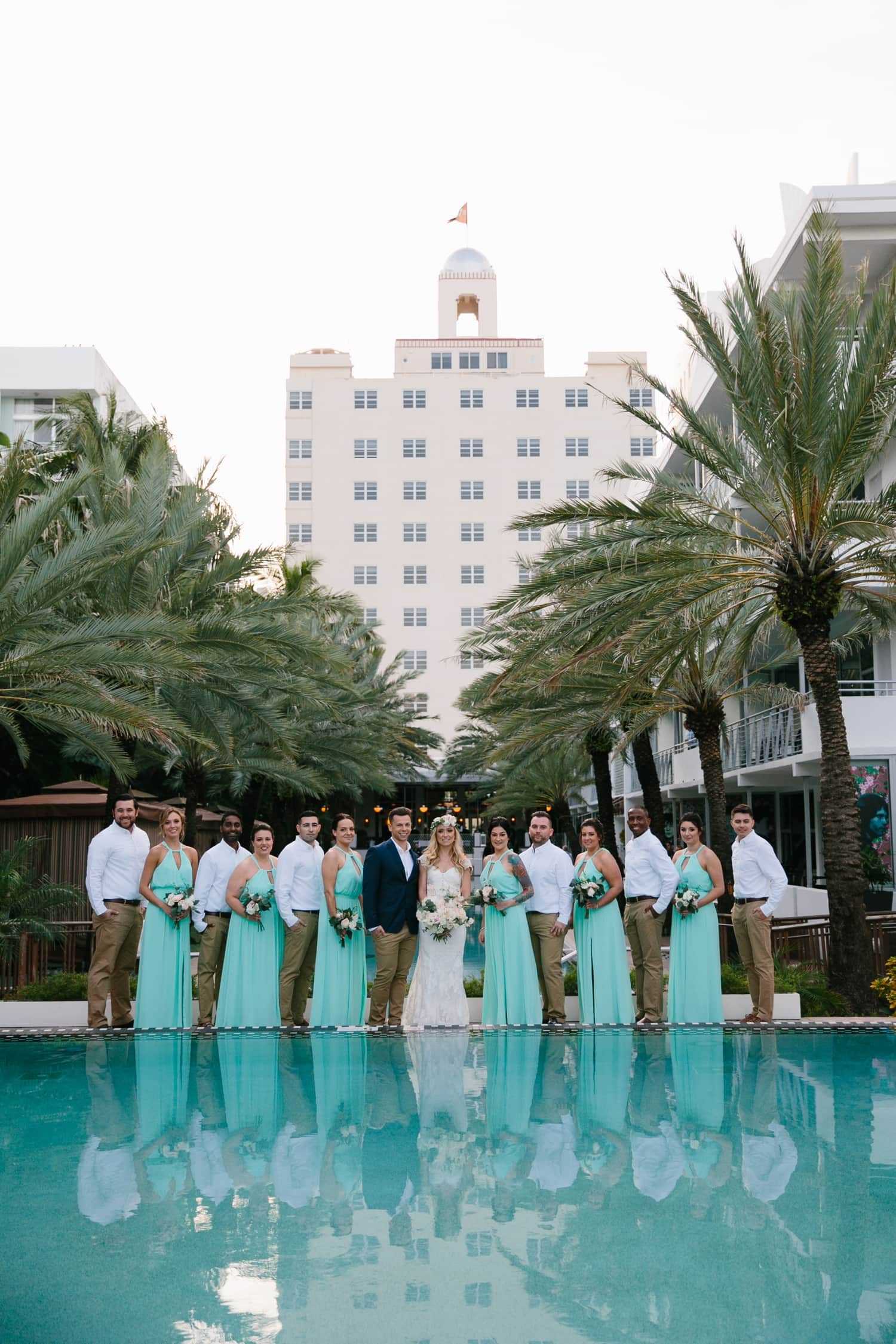 Wedding party Portrait. Turquoise bridesmaids dresses. Khaki pants and Blue Jacket Suit. Bride and Groom portrait. Winter Beach Wedding at the National Hotel in South Beach Fl